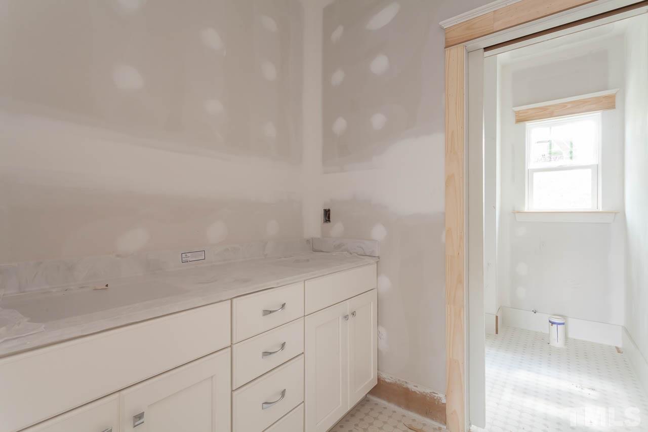 309 Georgetown Road Raleigh, NC 27608 - Photo 11 of 19 a bathroom with a granite countertop sink and white cabinets