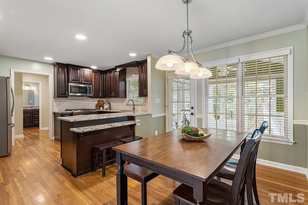 6103 Chesden Drive Durham, NC 27713 - Photo 6 of 22 a kitchen with stainless steel appliances granite countertop a stove a refrigerator a kitchen island a dining table and chairs