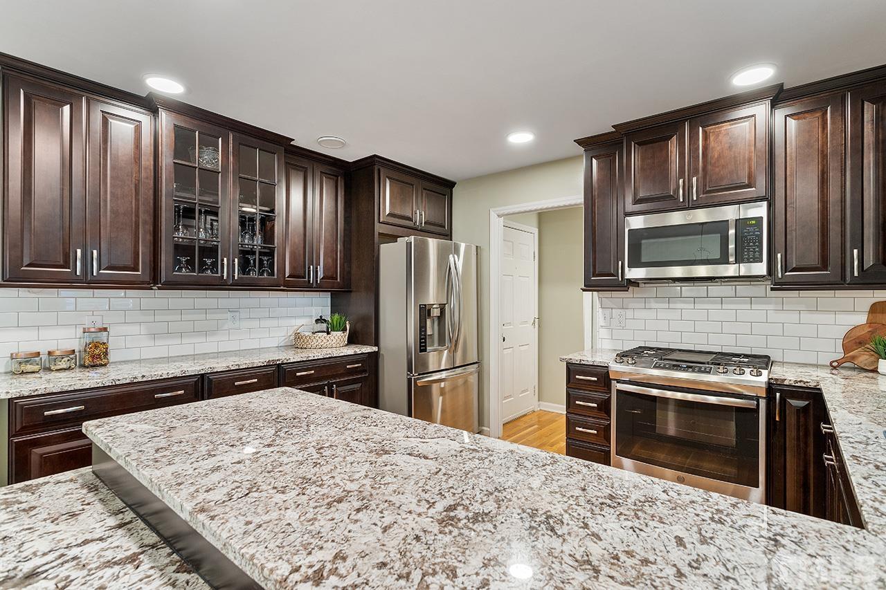 6103 Chesden Drive Durham, NC 27713 - Photo 7 of 22 a kitchen with stainless steel appliances granite countertop a refrigerator stove top oven and sink