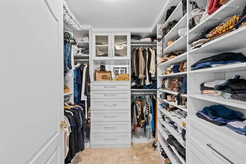a view of walk in closet with clothes and shoes
