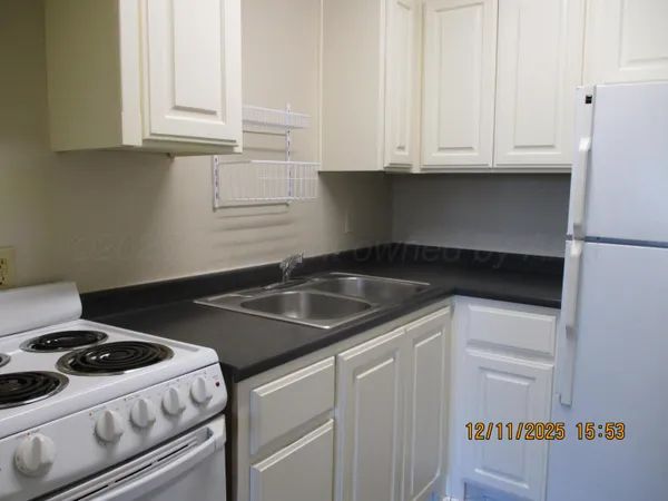a kitchen with granite countertop white cabinets and a stove a sink