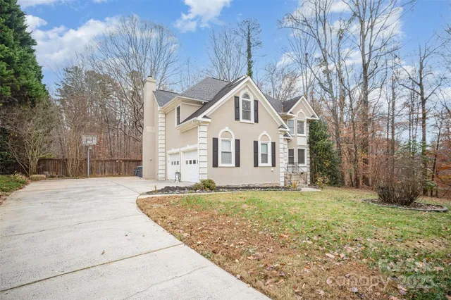 a view of a white house with a big yard and large trees