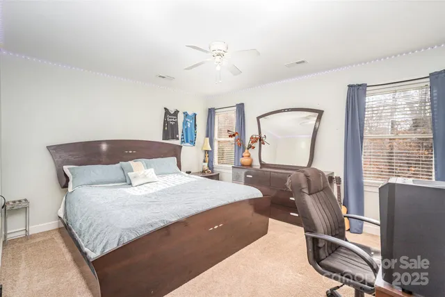a bedroom with a bed a computer on desk and a dresser next to a window
