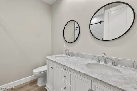 a bathroom with a granite countertop toilet a sink and a mirror