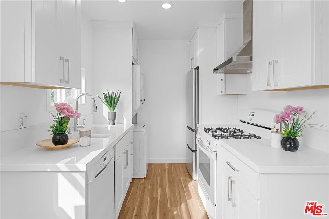 2948 Exposition Boulevard, Unit 7 Santa Monica, CA 90404 - Photo 8 of 15 a kitchen with stainless steel appliances a white center island cabinets and a potted plant