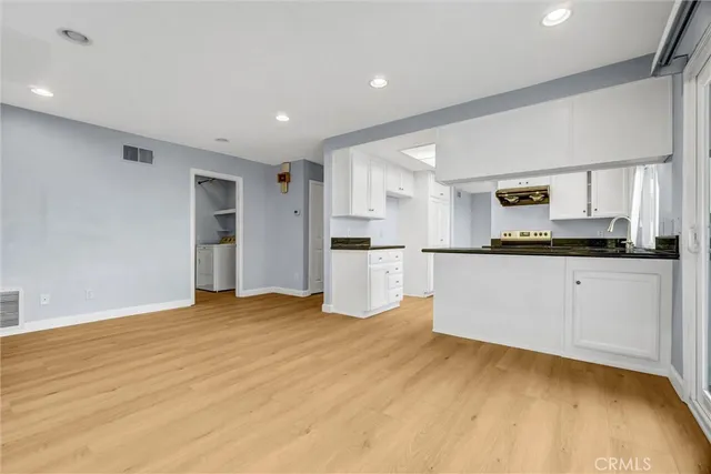 a view of a kitchen with refrigerator and white cabinets