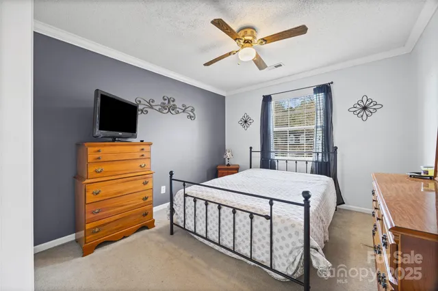 a bedroom with a bed a chandelier and a flat tv screen on dresser