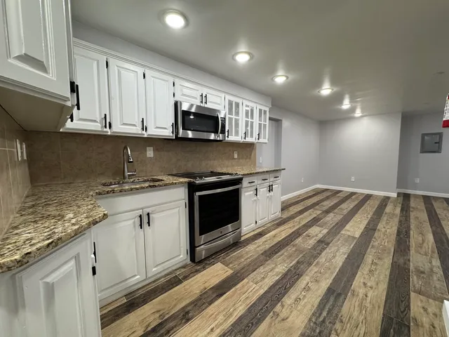 a kitchen with stainless steel appliances granite countertop a stove a sink and a microwave