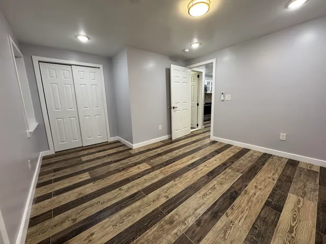 a view of a room with a bed and wooden floor