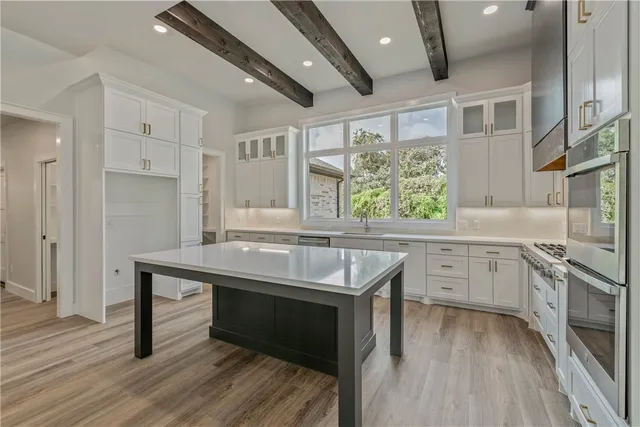 a kitchen with kitchen island granite countertop a stove a sink and wooden floors