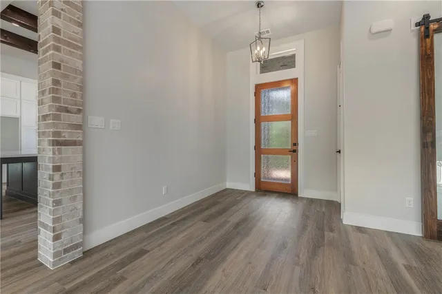 an empty room with wooden floor closet and windows