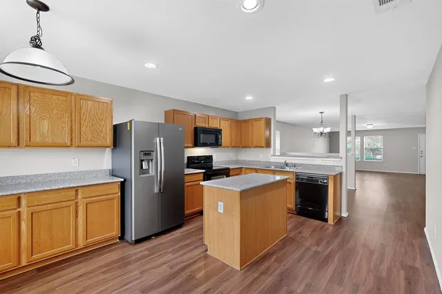 a kitchen with stainless steel appliances granite countertop a refrigerator a stove and a wooden floors