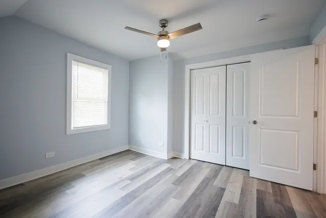 a view of a room with wooden floor fan and windows