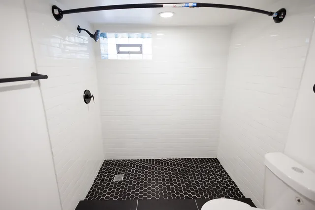 a white toilet sitting next to a shower