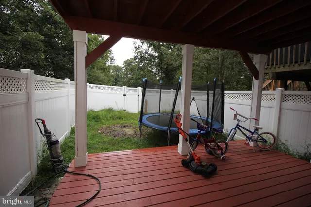 a view of a deck with couches and wooden floor next to a yard