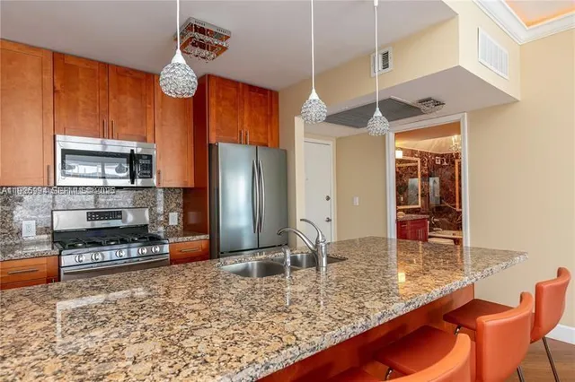 a kitchen with stainless steel appliances granite countertop a sink a stove and a refrigerator