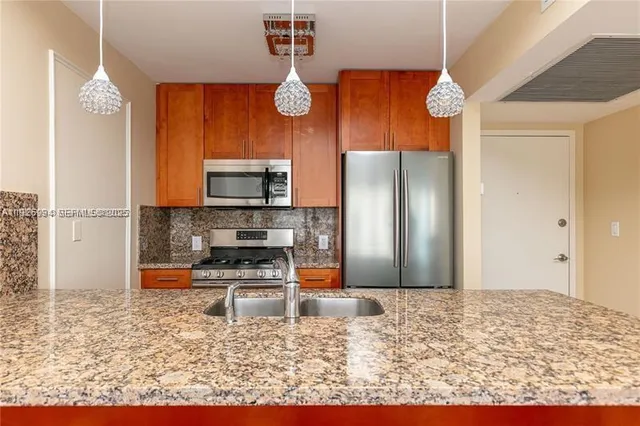 a kitchen with stainless steel appliances granite countertop a refrigerator a stove and a sink