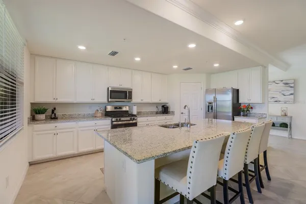 a kitchen with stainless steel appliances granite countertop a stove top oven a sink a refrigerator and white cabinets