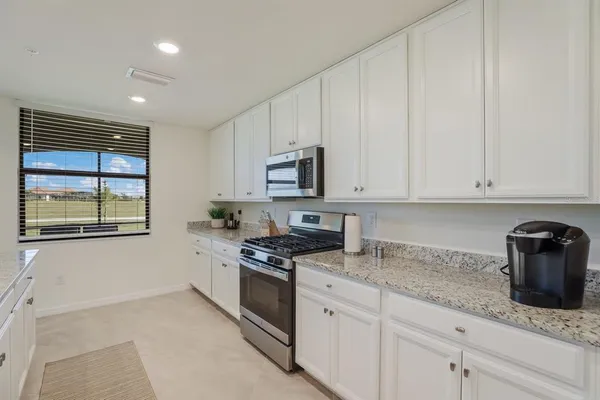 a kitchen with granite countertop white cabinets and stainless steel appliances