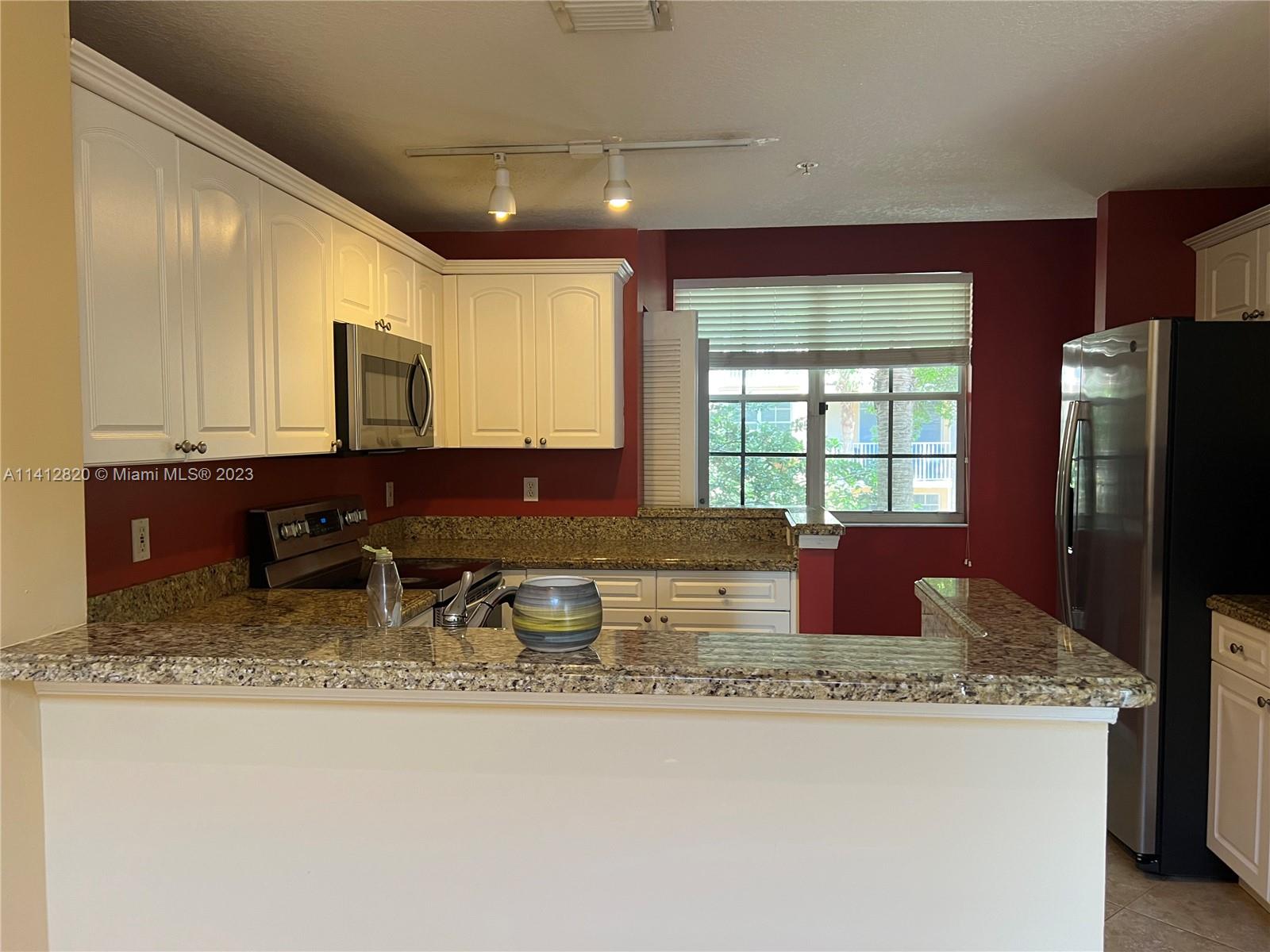 4812 Central Boulevard, Unit 20 Jupiter, FL 33458 - Photo 4 of 24 a kitchen with granite countertop a sink a stove and refrigerator