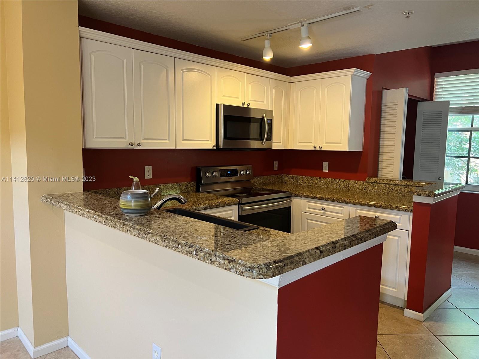4812 Central Boulevard, Unit 20 Jupiter, FL 33458 - Photo 5 of 24 a kitchen with granite countertop a sink a stove top oven a granite counter space and cabinets