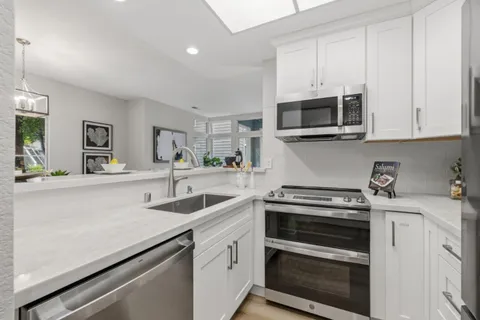 a kitchen with stainless steel appliances granite countertop grey cabinets a stove a sink and dishwasher