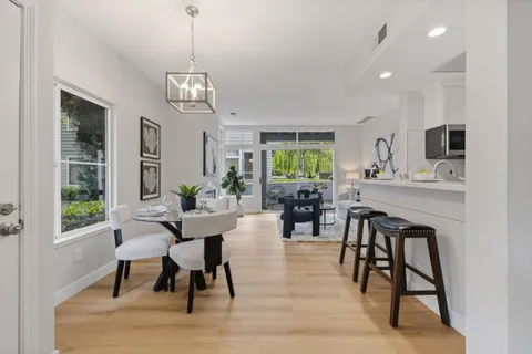 a dining room with wooden floor a chandelier a wooden table and chairs