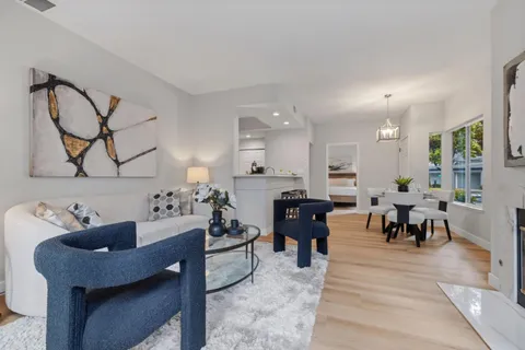 a living room with furniture kitchen view and a wooden floor