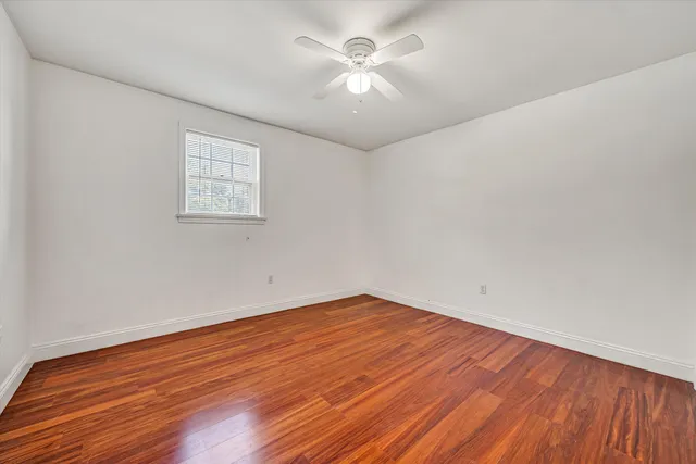 an empty room with wooden floor and a ceiling fan