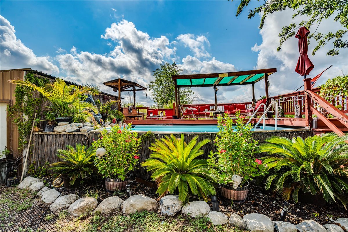 Lush tropical plantings surround an elevated swimming pool and wood-decked outdoor living spaces.