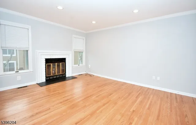 a view of empty room with wooden floor and fireplace