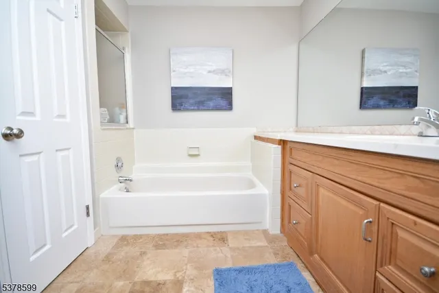 a spacious bathroom with a tub sink and mirror
