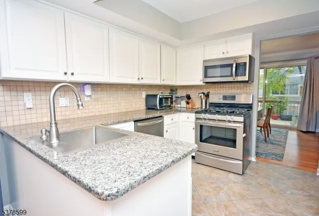 a kitchen with granite countertop white cabinets and appliances