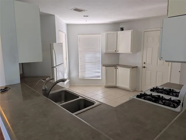 a view of an empty room with window and cabinet area