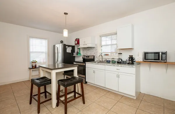a kitchen that has a lot of white cabinets and stainless steel appliances