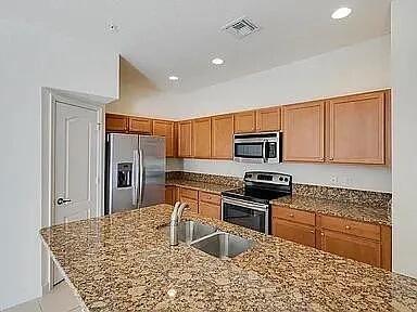 3047 Southwest Otter Lane Stuart, FL 34997 - Photo 3 of 12 a kitchen with stainless steel appliances granite countertop a stove top oven a sink a dining table and chairs