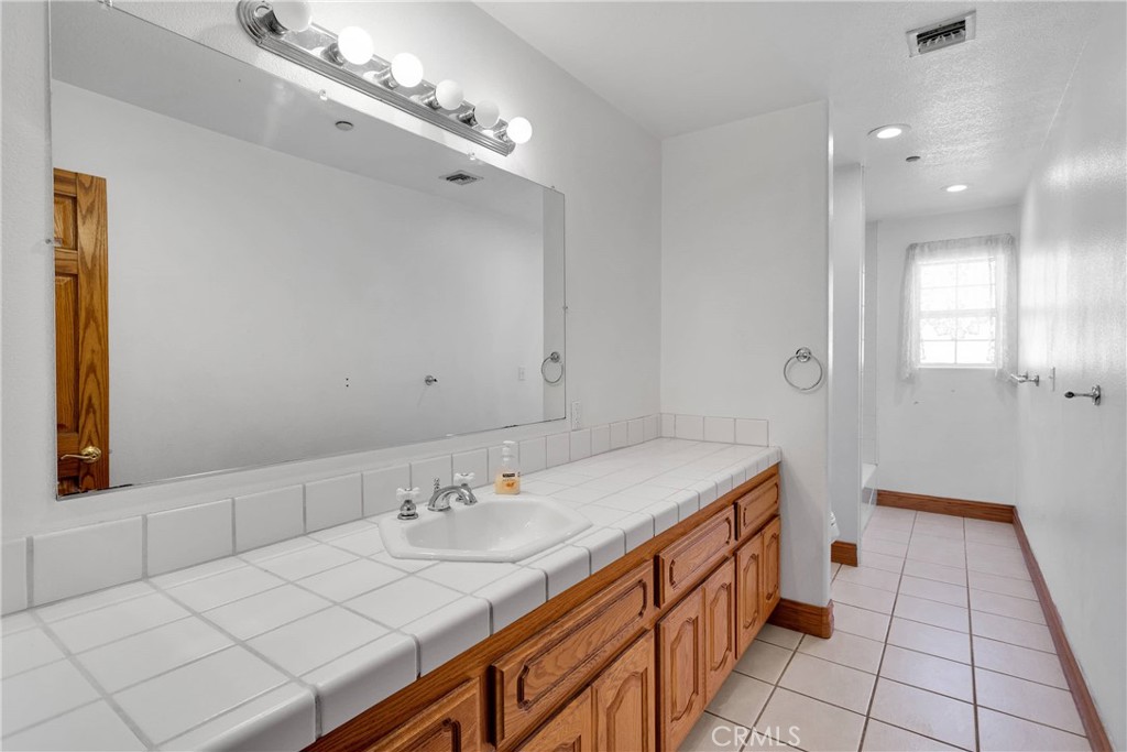 8381 White Road Phelan, CA 92371 - Photo 24 of 59 a spacious bathroom with a double vanity sink a mirror and a shower
