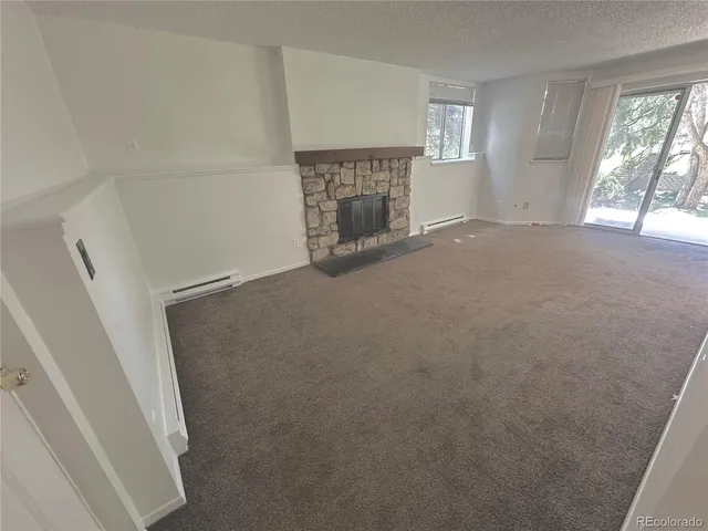 an empty room with windows and fireplace