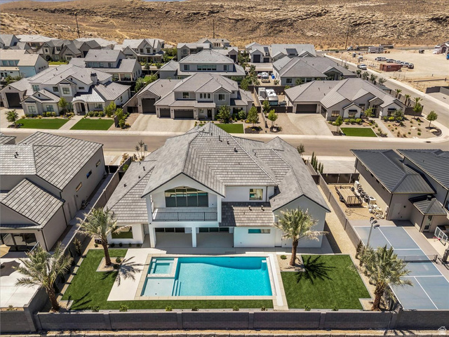 1620 Belayer Drive St. George, UT 84770 - Photo 50 of 51 Modern residential property featuring a multi-level design, a private swimming pool with an integrated spa, an expansive turf lawn, mature palm trees, and a dedicated sports court