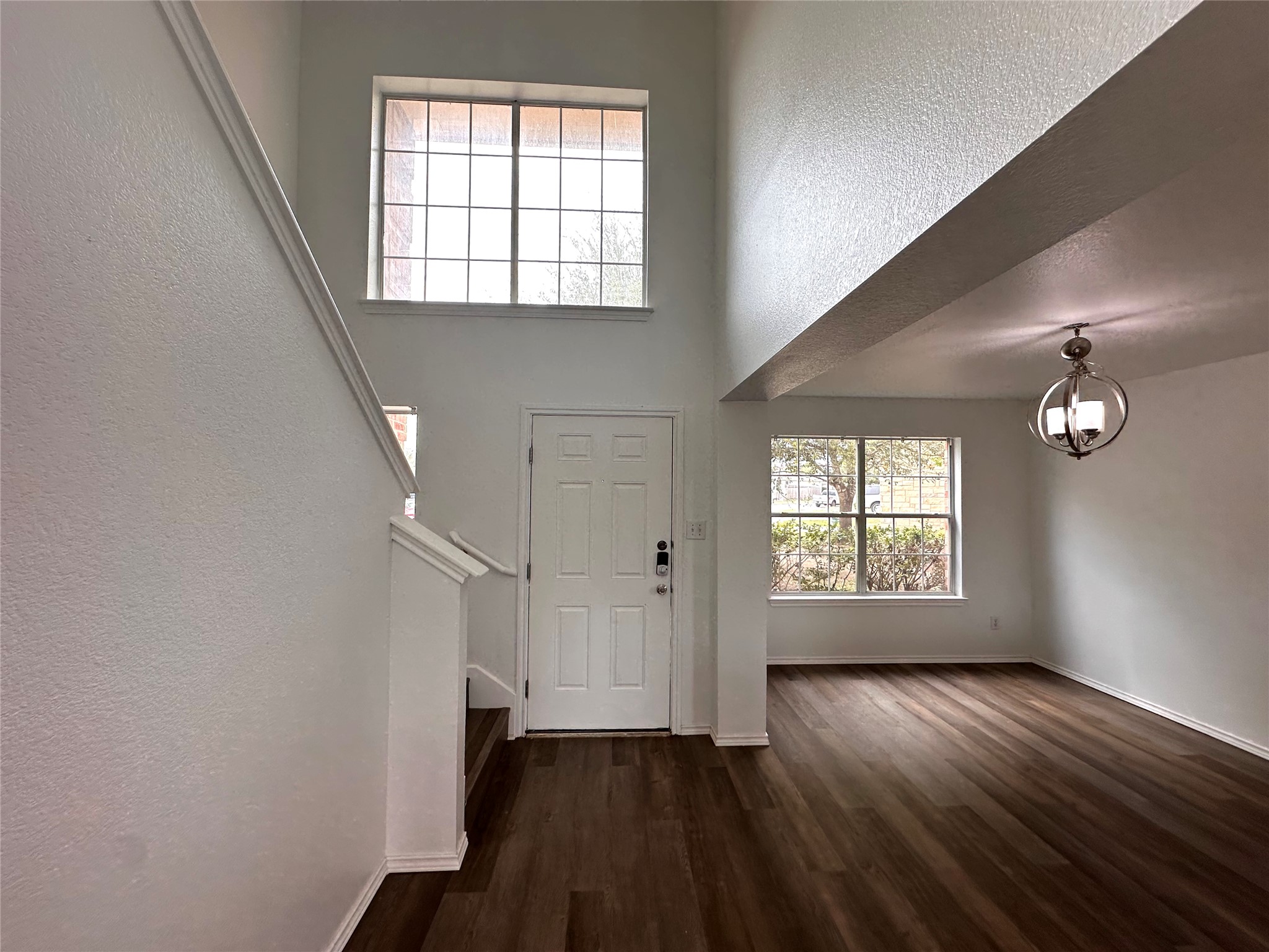722 Lavaca Loop Elgin, TX 78621 - Photo 2 of 24 Entrance foyer featuring plenty of natural light, a high ceiling, a textured wall, and dark wood finished floors