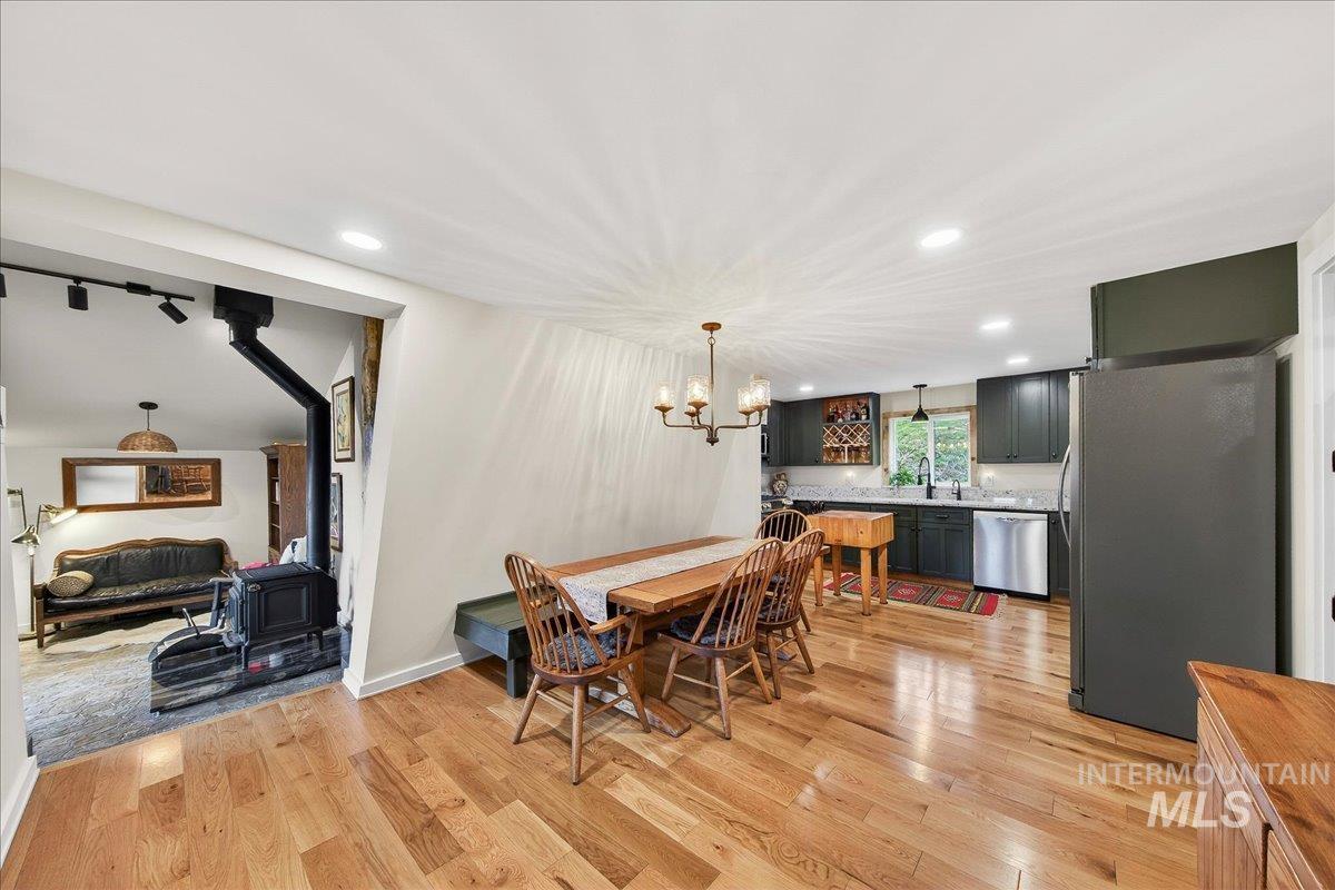 239 Tollgate Road Boise, ID 83716 - Photo 14 of 50 Dining space featuring a wood stove, light wood-style flooring, and a chandelier