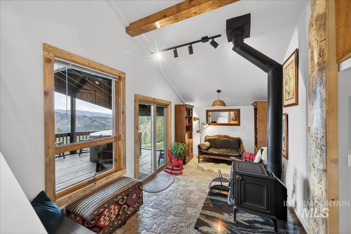 239 Tollgate Road Boise, ID 83716 - Photo 18 of 50 Living area featuring a wood stove, light stone finish floors, and vaulted ceiling with beams