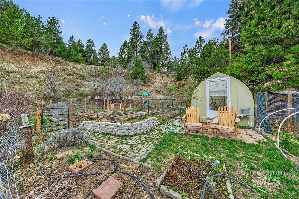 239 Tollgate Road Boise, ID 83716 - Photo 49 of 50 Fenced backyard with a vegetable garden, an outdoor structure, view of scattered trees, and an exterior structure