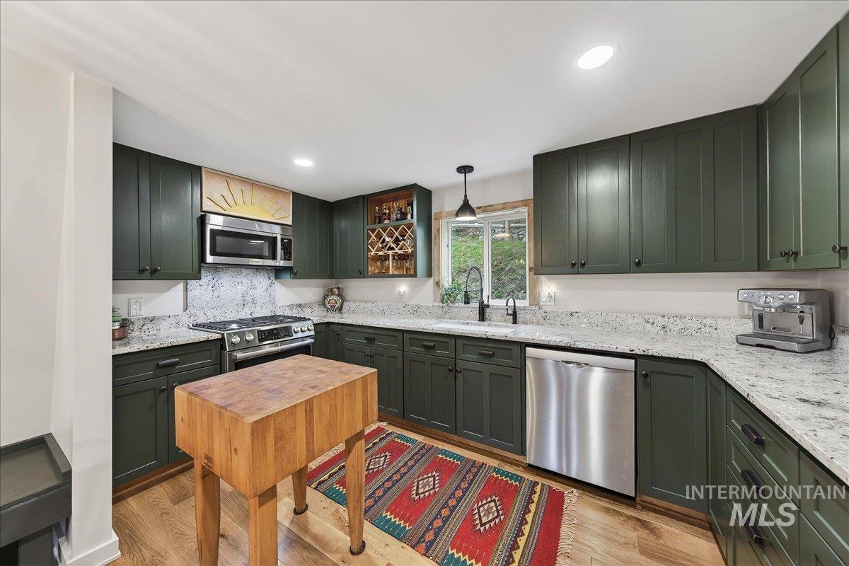 239 Tollgate Road Boise, ID 83716 - Photo 6 of 50 Kitchen with stainless steel appliances, light stone counters, light wood-style flooring, and green cabinets