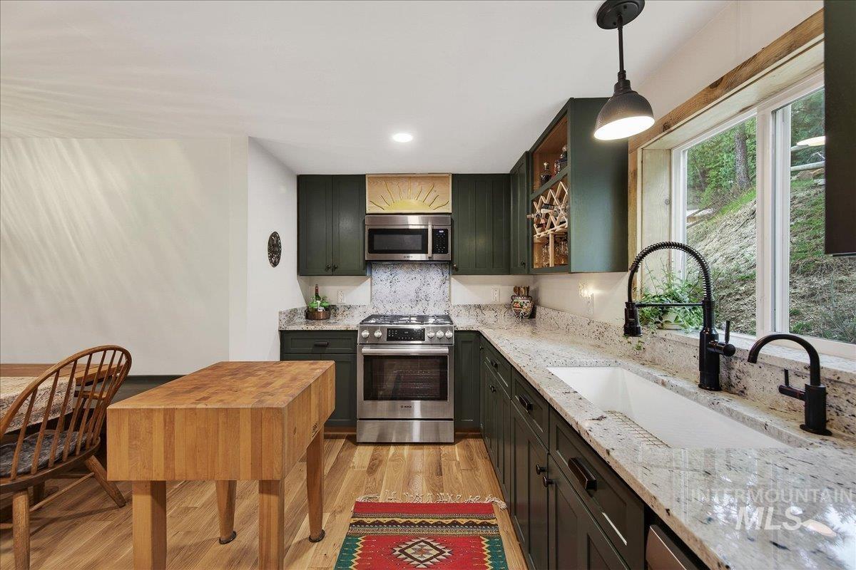 239 Tollgate Road Boise, ID 83716 - Photo 8 of 50 Kitchen featuring stainless steel appliances, light wood-type flooring, light stone countertops, glass insert cabinets, and pendant lighting
