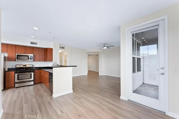 a kitchen with stainless steel appliances granite countertop a refrigerator a sink a stove a microwave and island with wooden floor