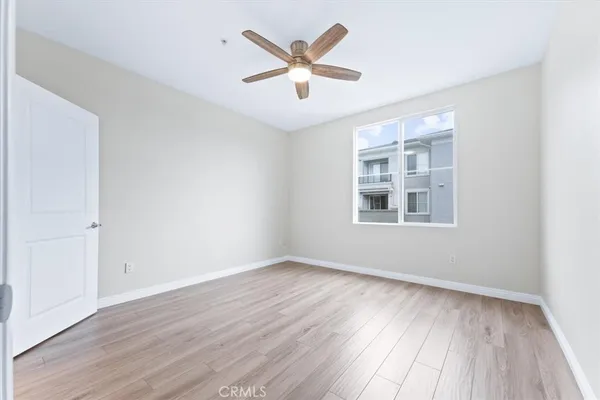 an empty room with wooden floor ceiling fan and windows