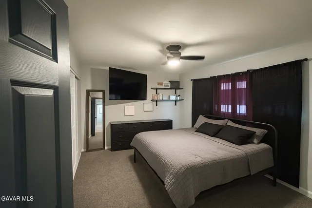 a bedroom with a bed a television and a large window