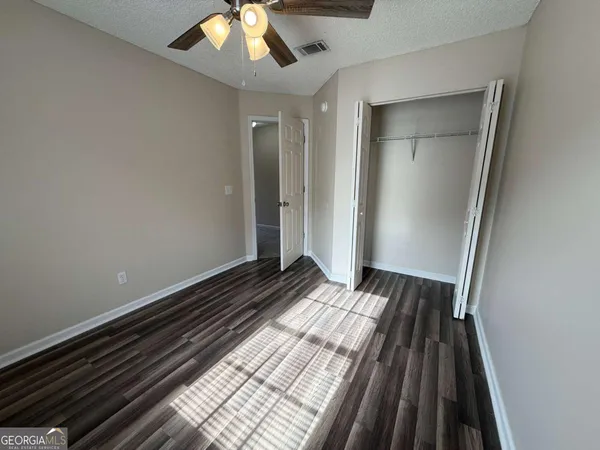 a view of empty room with wooden floor and fan