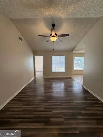 an empty room with windows and ceiling fan